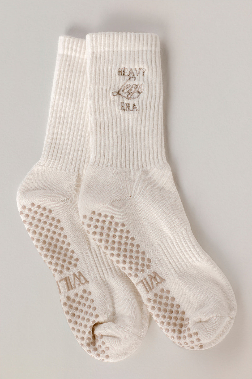 White socks with textured grip sole on a light gray background. Socks say Heavy Legs Era.