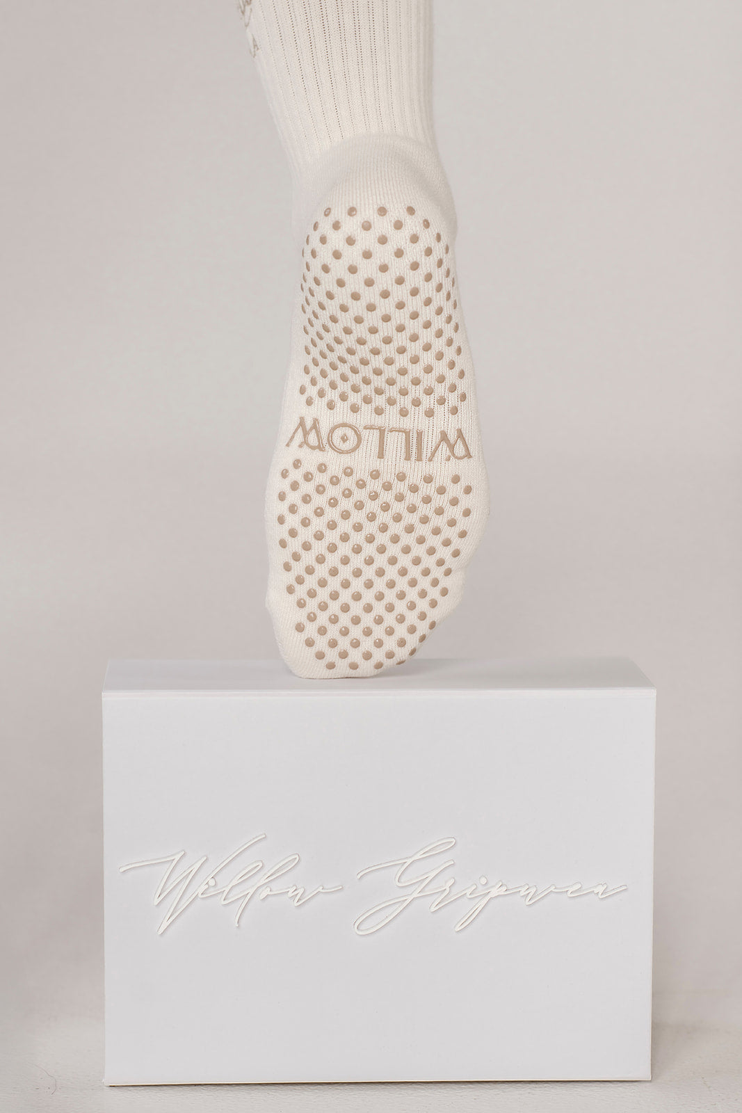 White sock with textured grip sole on a light gray background. Grip says Willow.