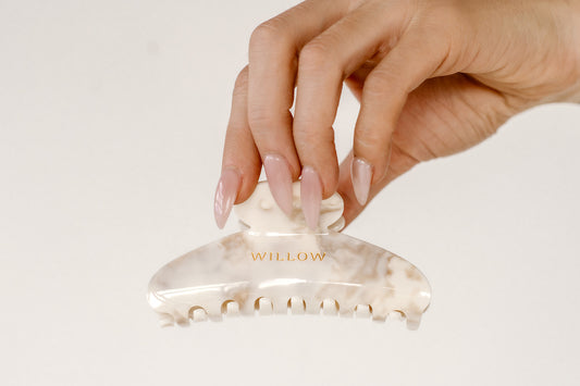 Hand holding a beige hair clip with 'WILLOW' branding on a light background