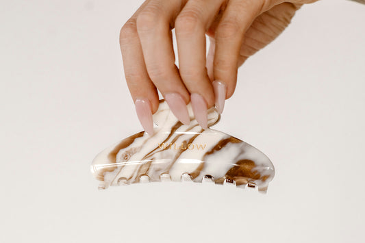 Marbled hair clip held by a hand on a light background