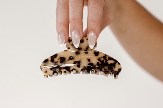 Hand holding a tortoiseshell patterned hair clip with 'WILLOW' branding on a light background
