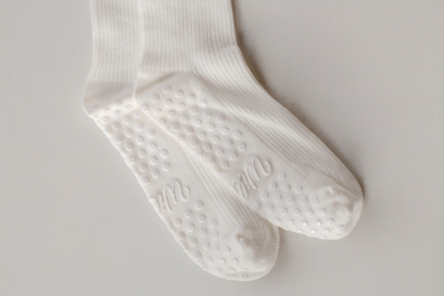 White socks with textured grip sole on a light gray background. The grip says Willow in cursive. White grips. 