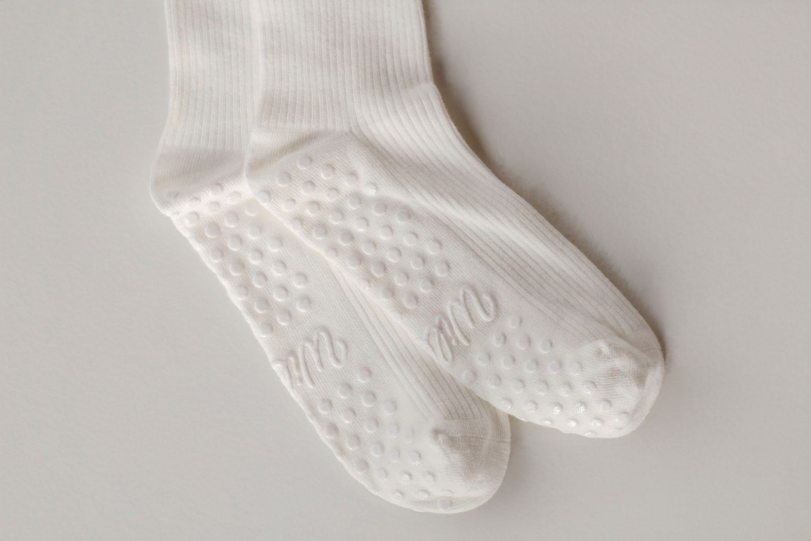 White socks with textured grip sole on a light gray background. The grip says Willow in cursive. White grips. 